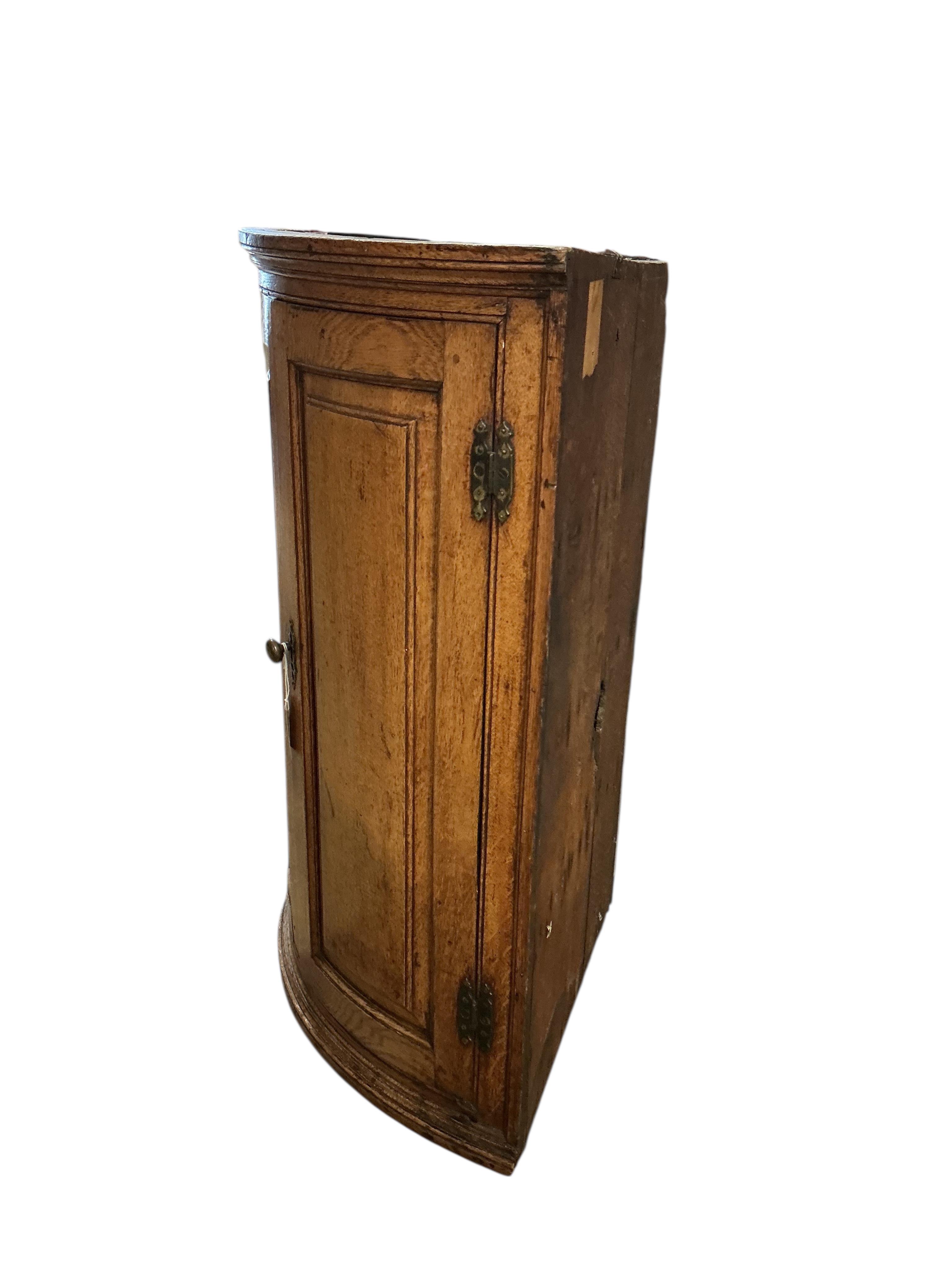 An early 19th century oak bowfront hanging corner cupboard, width 72cm, depth 49cm, height 97cm.